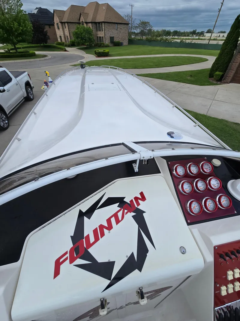 Slide: The Image of 2004 Fountain 47 Lightning boat with dashboard and logo, parked in residential driveway. - 3
