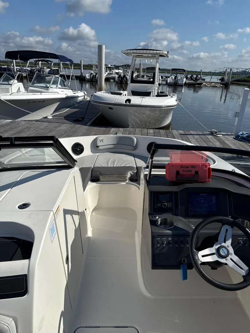 Slide: The Image of 2022 Bayliner VR6 Bowrider OB at marina, featuring helm and seating area. - 7
