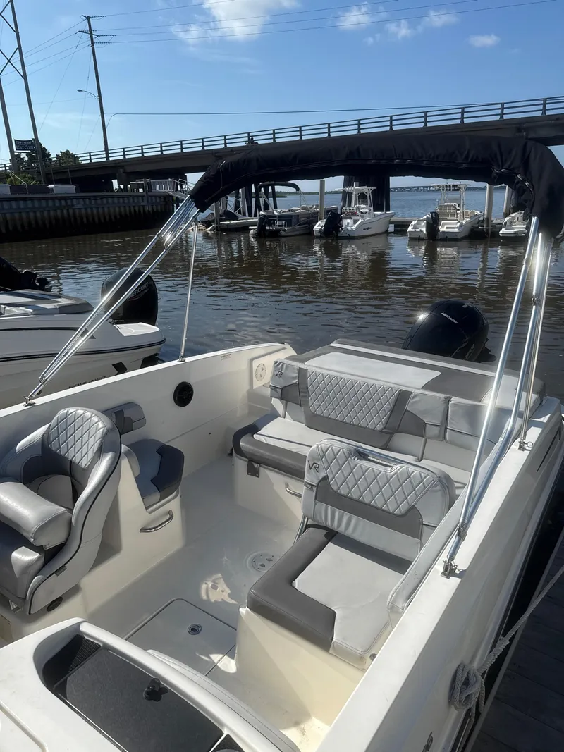 Slide: The Image of 2022 Bayliner VR6 Bowrider OB with sleek seating, docked near a bridge on a sunny day. - 8