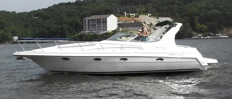 Slide: The Image of 1999 Cruisers Yachts 3375 Esprit on water, with scenic background and modern design. - 1