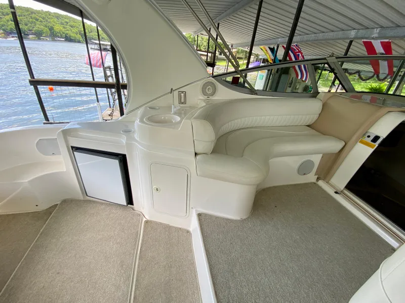 Slide: The Image of 1999 Cruisers Yachts 3375 Esprit interior with seating and mini fridge, docked by a lake. - 13