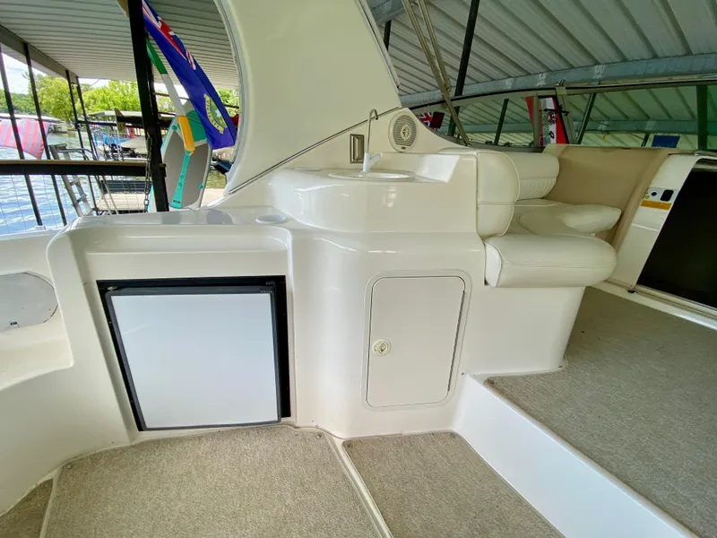 Slide: The Image of 1999 Cruisers Yachts 3375 Esprit interior with seating and mini fridge in a covered dock. - 14