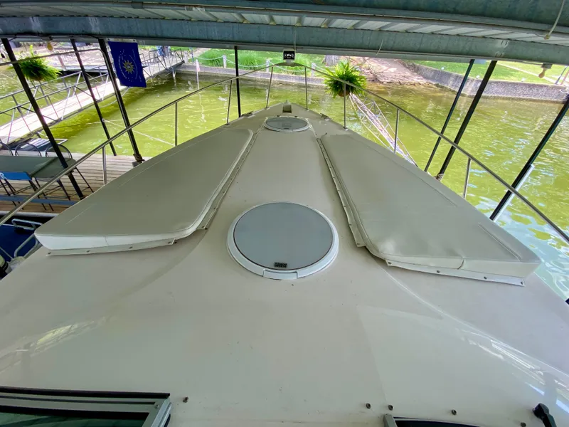 Slide: The Image of 1999 Cruisers Yachts 3375 Esprit boat deck under covered dock, with water and greenery visible. - 18