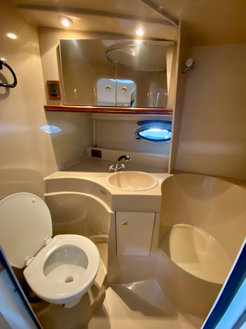 Slide: The Image of 1999 Cruisers Yachts 3375 Esprit bathroom with toilet, sink, mirror, and porthole window. - 29