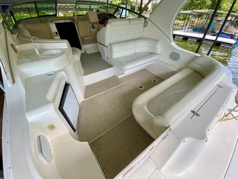 Slide: The Image of 1999 Cruisers Yachts 3375 Esprit interior with white seating and helm, docked by the water. - 7