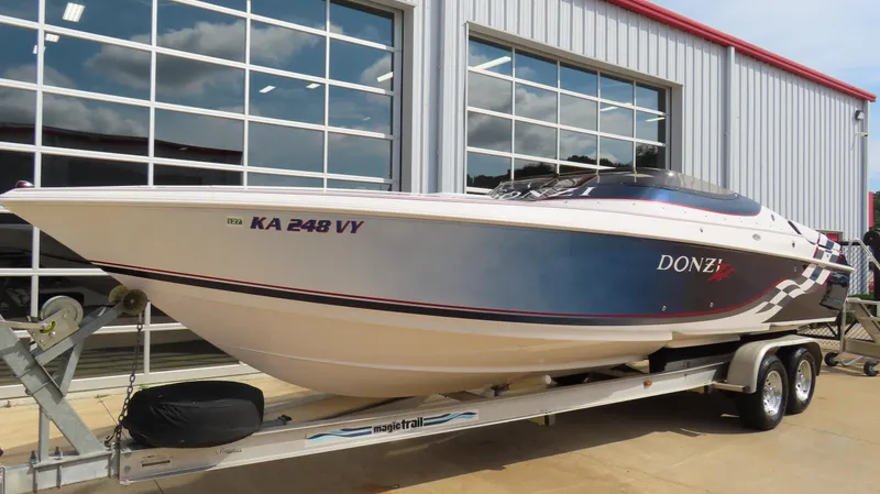 Slide: The Image of 2000 Donzi 28ZX speedboat on trailer, parked outside a garage with glass doors. - 2