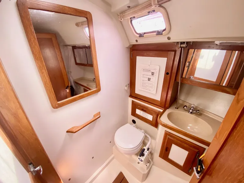 Slide: The Image of 1995 Catalina 36 MkII yacht bathroom with sink, toilet, mirror, and wooden cabinetry. - 50