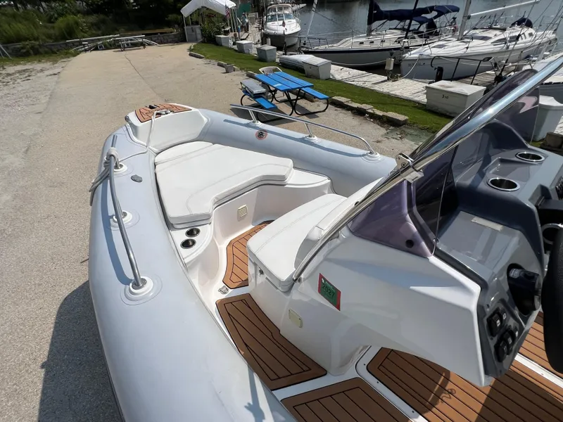 Slide: The Image of 2019 Grand G580HLF boat with white seating and wooden deck, docked near sailboats. - 11
