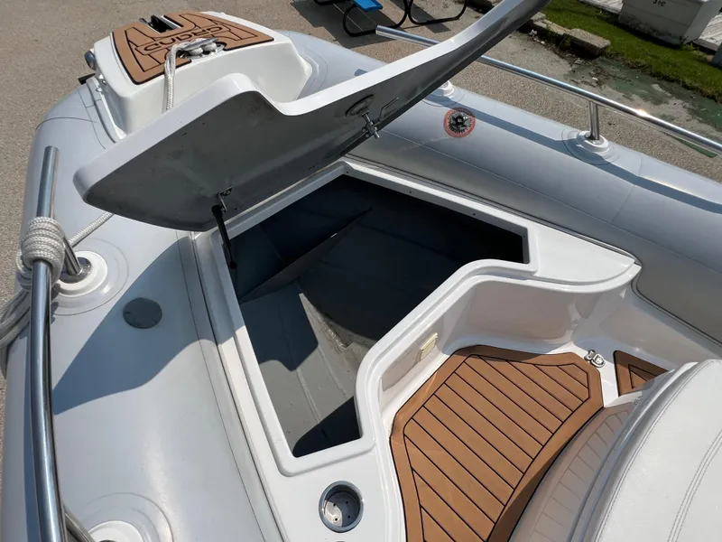Slide: The Image of Open storage compartment on a 2019 Grand G580HLF inflatable boat with teak flooring. - 12