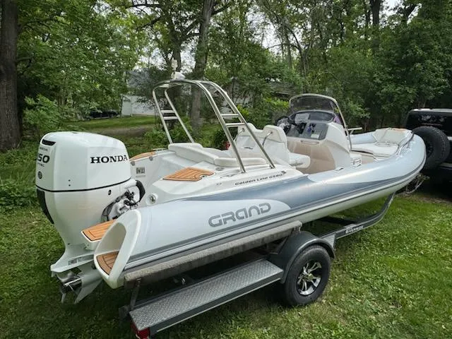 Slide: The Image of 2019 Grand G580HLF boat with Honda engine on trailer, parked on grass. - 17