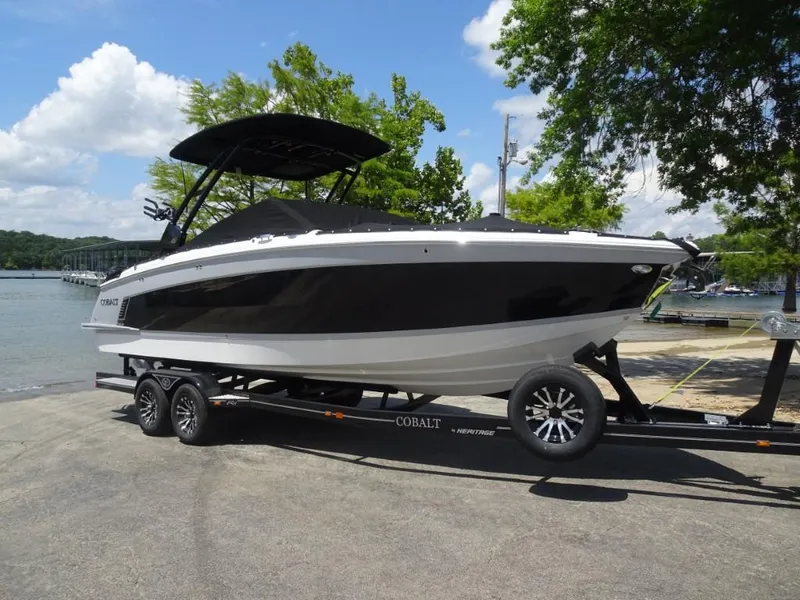 The Image of 2025 Cobalt R8 Surf boat on trailer by a lake, under a clear sky. - 0