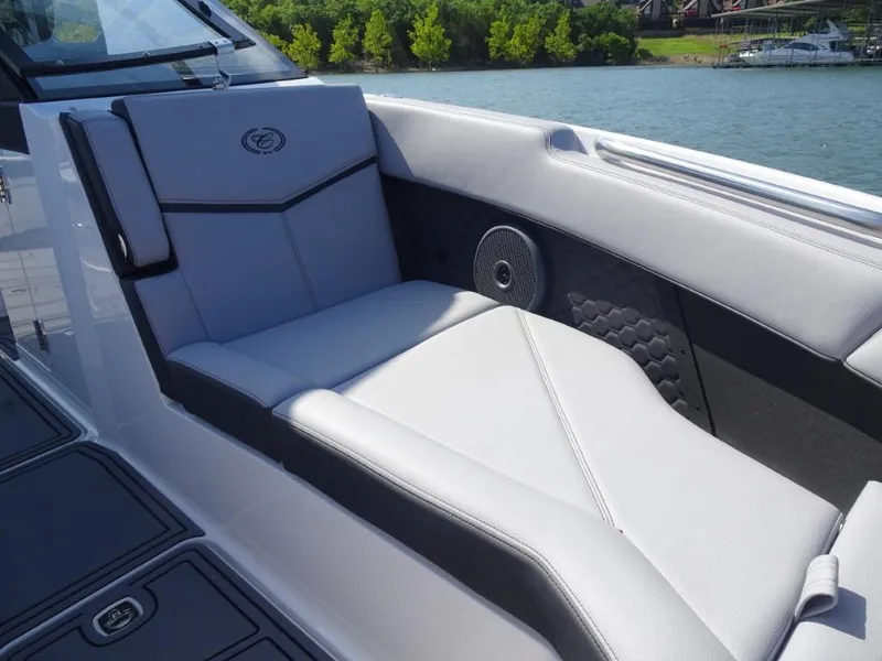 Slide: The Image of 2025 Cobalt R8 Surf boat interior with luxurious seating and speaker, near a scenic lake. - 23