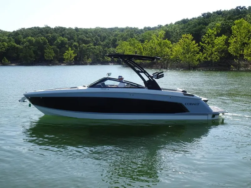Slide: The Image of 2025 Cobalt R8 Surf boat on a serene lake with lush green trees. - 4