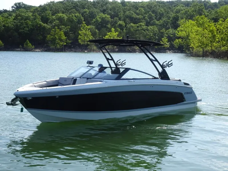 Slide: The Image of 2025 Cobalt R8 Surf boat on a serene lake with lush green trees. - 5