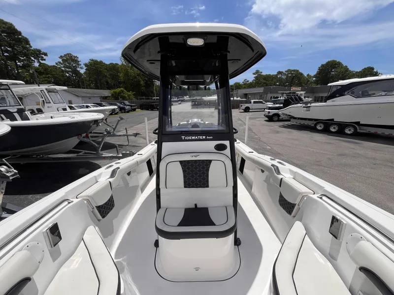 Slide: The Image of 2023 Tidewater 232 LXF boat interior with seating, console, and clear sky background. - 11