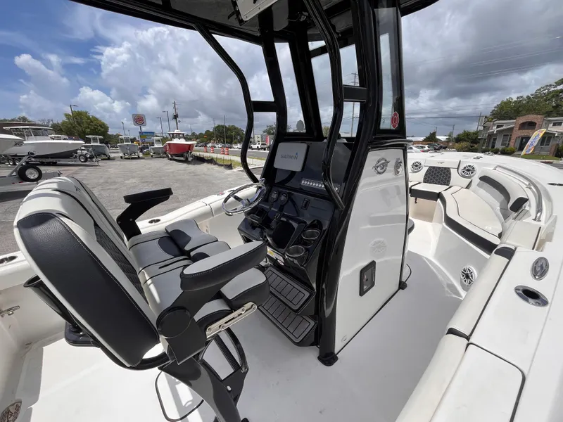 Slide: The Image of 2023 Tidewater 232 LXF boat interior with modern helm and seating under cloudy sky. - 13