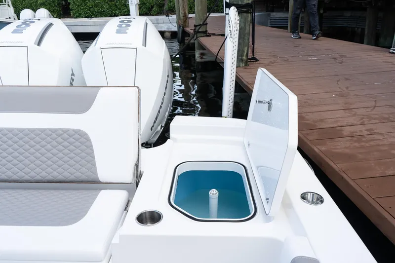 Slide: The Image of 2025 Caymas 291 HB boat with open storage compartment and dual Mercury engines at dock. - 11