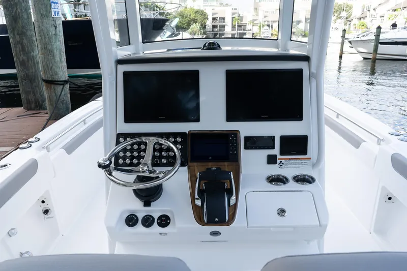 Slide: The Image of 2025 Caymas 291 HB boat dashboard with dual screens and steering wheel, docked at marina. - 12