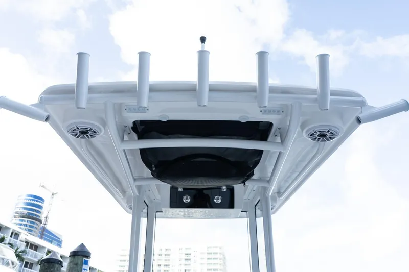 Slide: The Image of 2025 Caymas 291 HB boat T-top with rod holders and speakers against a clear sky. - 15