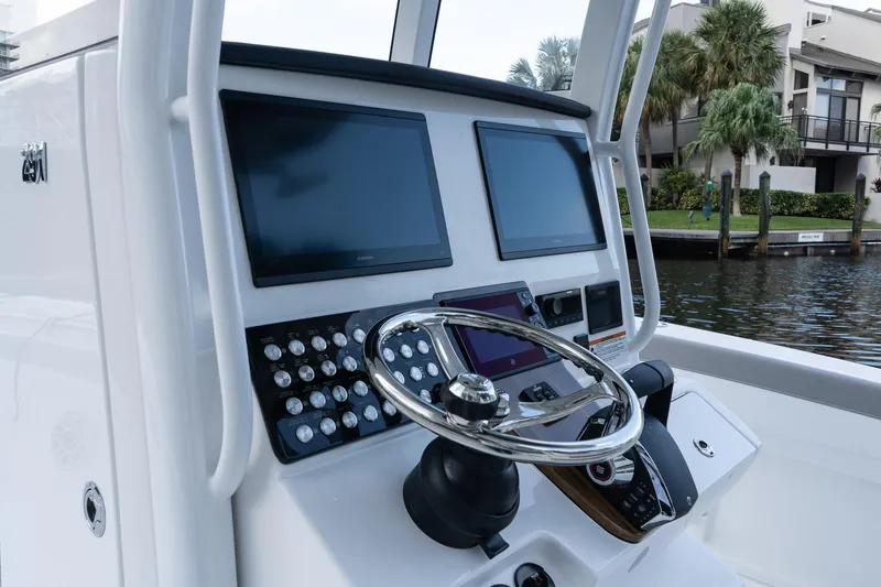 Slide: The Image of 2025 Caymas 291 HB boat dashboard with dual screens and steering wheel, dockside view. - 22
