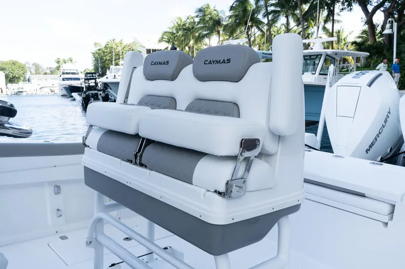 Slide: The Image of 2025 Caymas 291 HB boat seating with luxurious white and gray upholstery, docked near palm trees. - 24