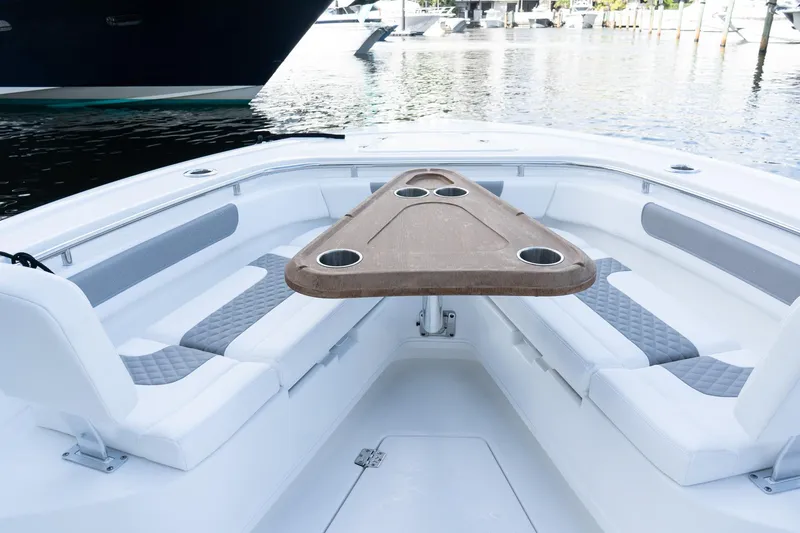 Slide: The Image of 2025 Caymas 291 HB boat interior with cushioned seating and wooden table, docked by the water. - 26