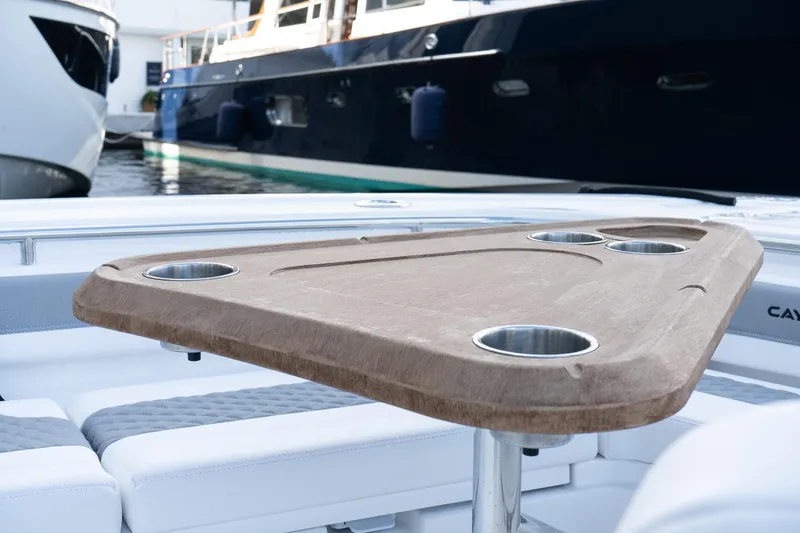 Slide: The Image of 2025 Caymas 291 HB boat with wooden table and cup holders, docked near other yachts. - 29