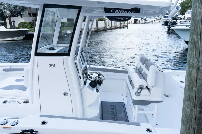 Slide: The Image of 2025 Caymas 291 HB boat interior with helm and seating, docked by the water. - 3