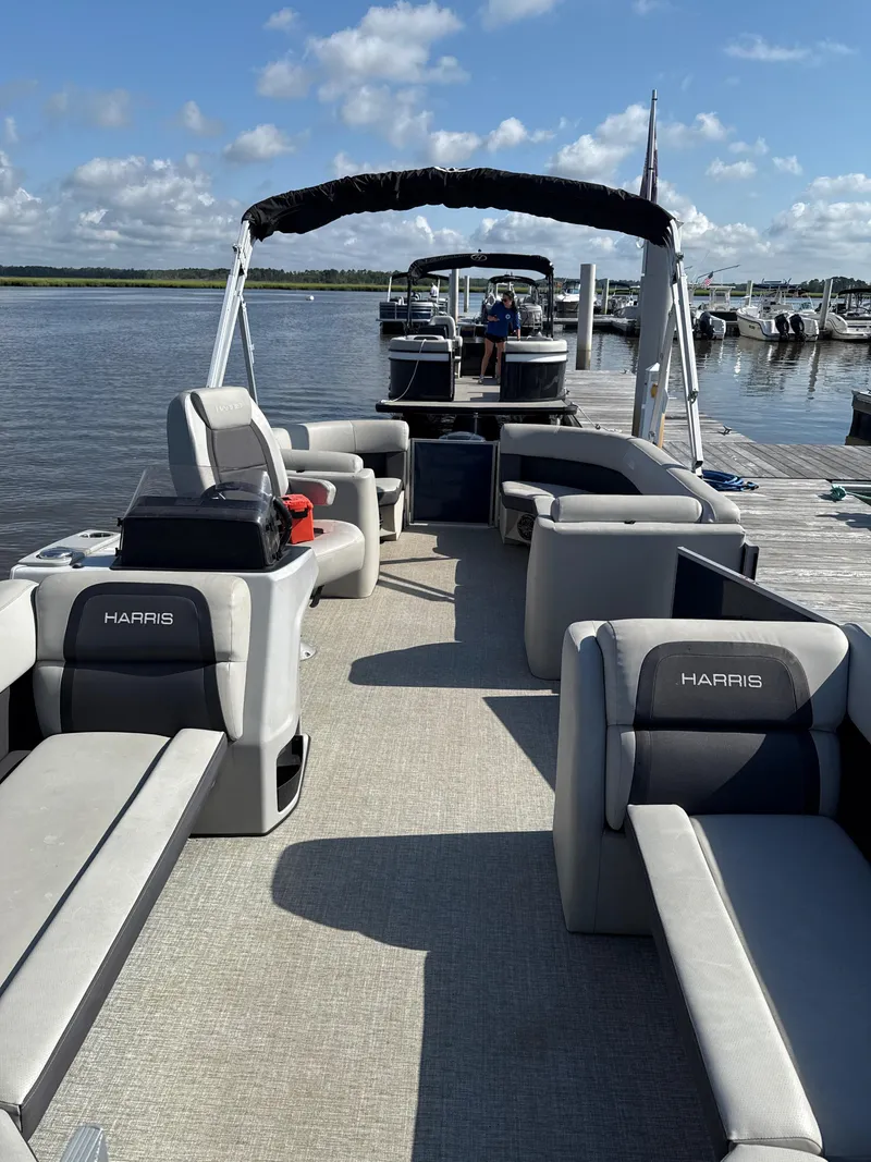 Slide: The Image of 2024 Harris Cruiser 230 pontoon boat docked, featuring spacious seating and modern design. - 2