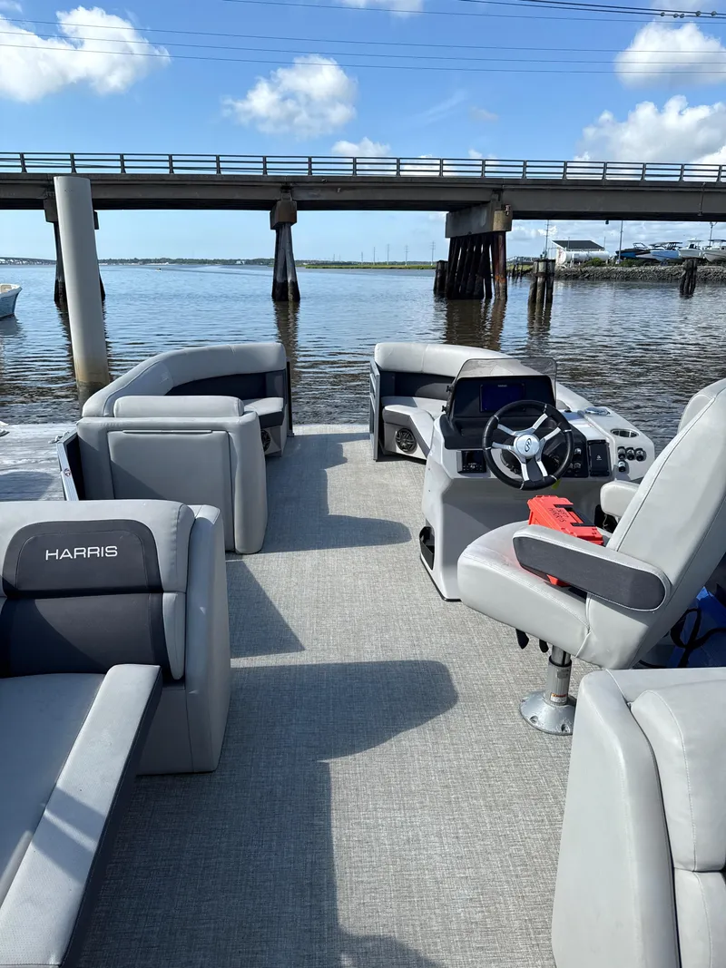 Slide: The Image of 2024 Harris Cruiser 230 pontoon boat interior with gray seating, steering console, and bridge view. - 3