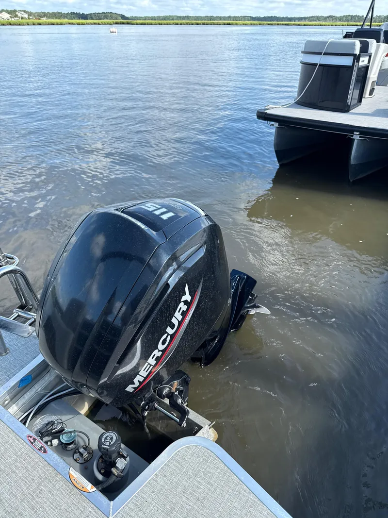 Slide: The Image of 2024 Harris Cruiser 230 with Mercury outboard motor on a calm lake. - 5