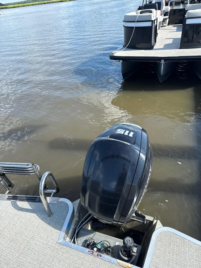 Slide: The Image of 2024 Harris Cruiser 230 pontoon boat with outboard motor on calm water. - 6