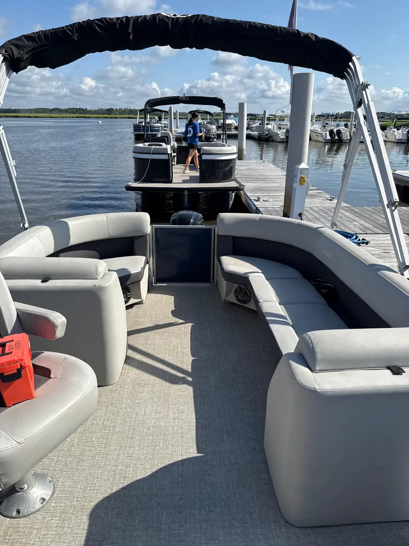 Slide: The Image of 2024 Harris Cruiser 230 pontoon boat with spacious seating, docked at a marina. - 7