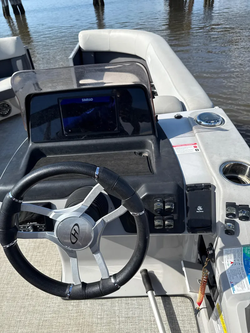 Slide: The Image of 2024 Harris Cruiser 230 boat dashboard with steering wheel and navigation system. - 8