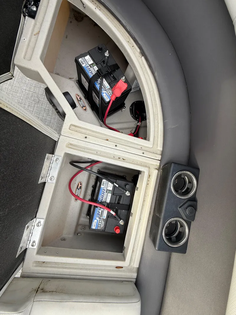 Slide: The Image of 2024 Harris Cruiser 230 boat battery compartment with dual batteries and cup holders. - 11