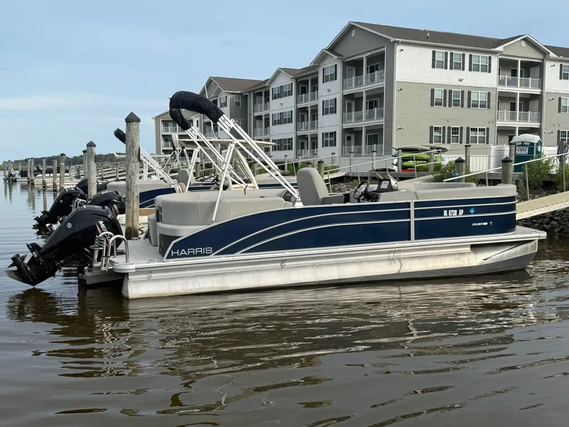 Slide: The Image of 2024 Harris Cruiser 230 pontoon boat docked near waterfront apartments. - 3