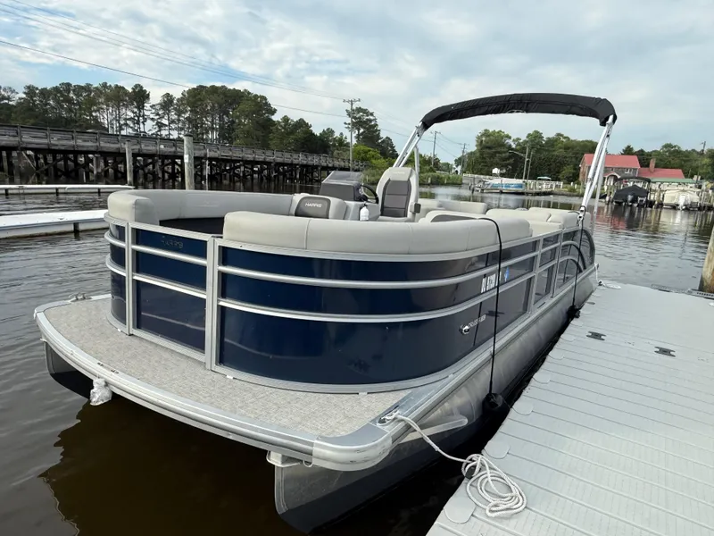 Slide: The Image of 2024 Harris Cruiser 230 pontoon boat docked on a calm river. - 4