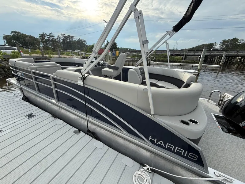 Slide: The Image of 2024 Harris Cruiser 230 pontoon boat docked by a scenic waterfront. - 5