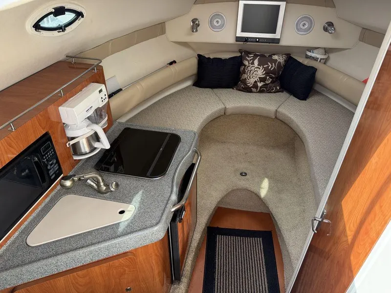 Slide: The Image of Interior of a 2006 Larson 240 Cabrio boat with kitchenette and cozy seating area. - 13