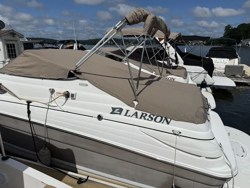 Slide: The Image of 2006 Larson 240 Cabrio boat docked with beige cover under blue sky. - 19