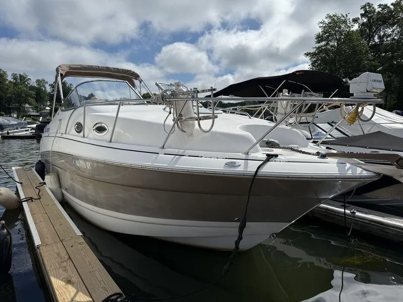 Slide: The Image of 2006 Larson 240 Cabrio boat docked at marina under cloudy sky. - 2