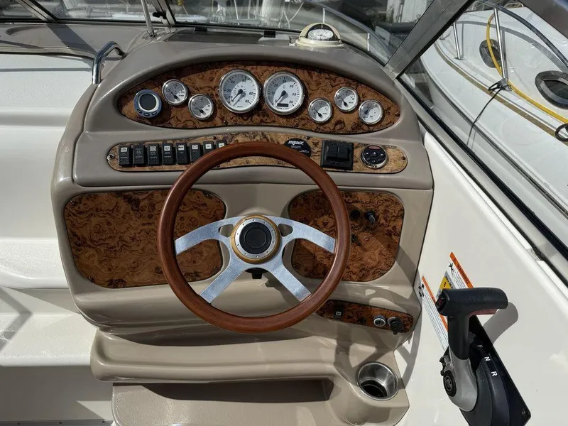 Slide: The Image of 2006 Larson 240 Cabrio boat dashboard with wood accents and steering wheel. - 7