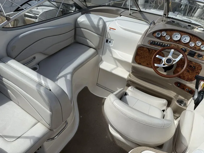 Slide: The Image of 2006 Larson 240 Cabrio boat interior with beige seating and wood-accented dashboard. - 9