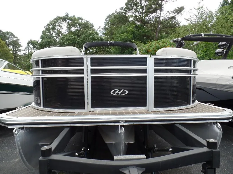 Slide: The Image of 2018 Harris Cruiser 240 pontoon boat on trailer, surrounded by trees and other boats. - 3