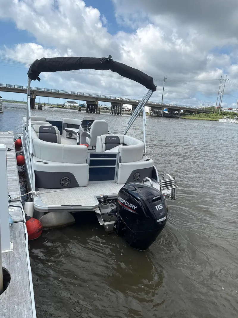 Slide: The Image of 2024 Harris Cruiser 230 pontoon boat docked, featuring a Mercury 115 outboard motor. - 4