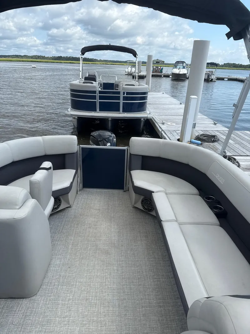 Slide: The Image of 2024 Harris Cruiser 230 pontoon boat interior at dock, featuring spacious seating and modern design. - 5