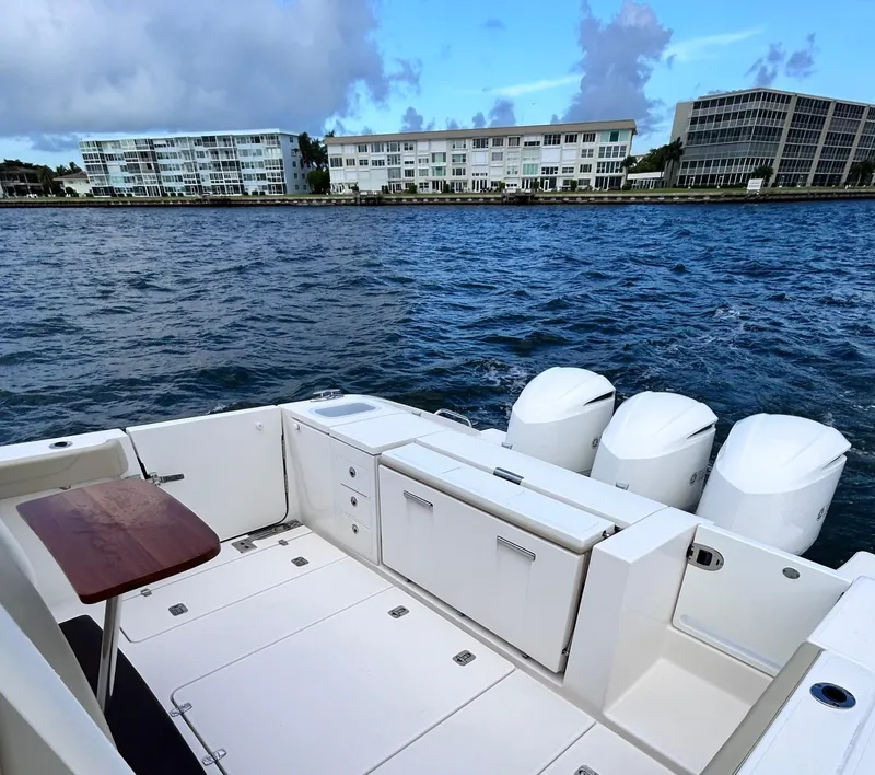 Slide: The Image of 2018 Pursuit S 368 Sport boat with triple engines, docked near waterfront buildings. - 13