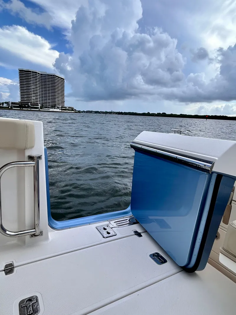 Slide: The Image of 2018 Pursuit S 368 Sport boat with open side door, overlooking water and cloudy sky. - 17