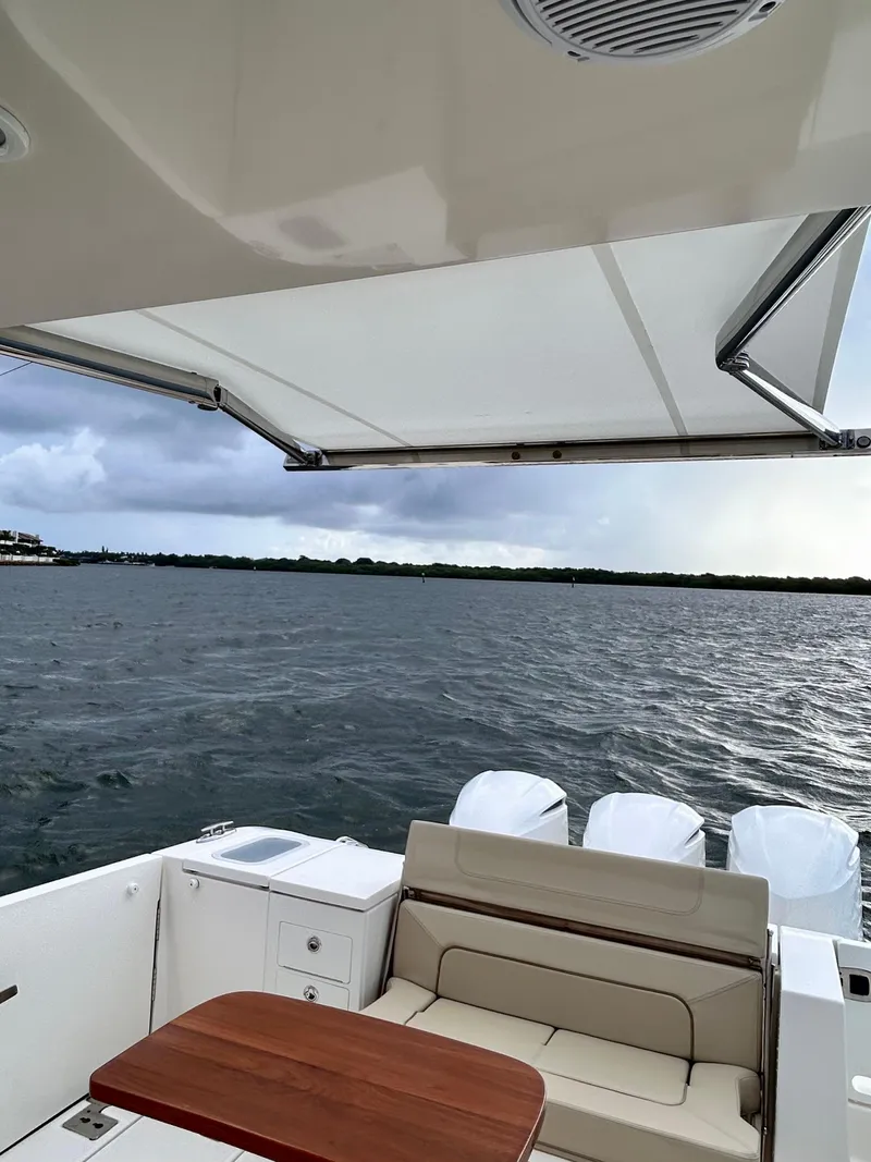 Slide: The Image of 2018 Pursuit S 368 Sport boat with seating, table, and canopy on open water. - 20