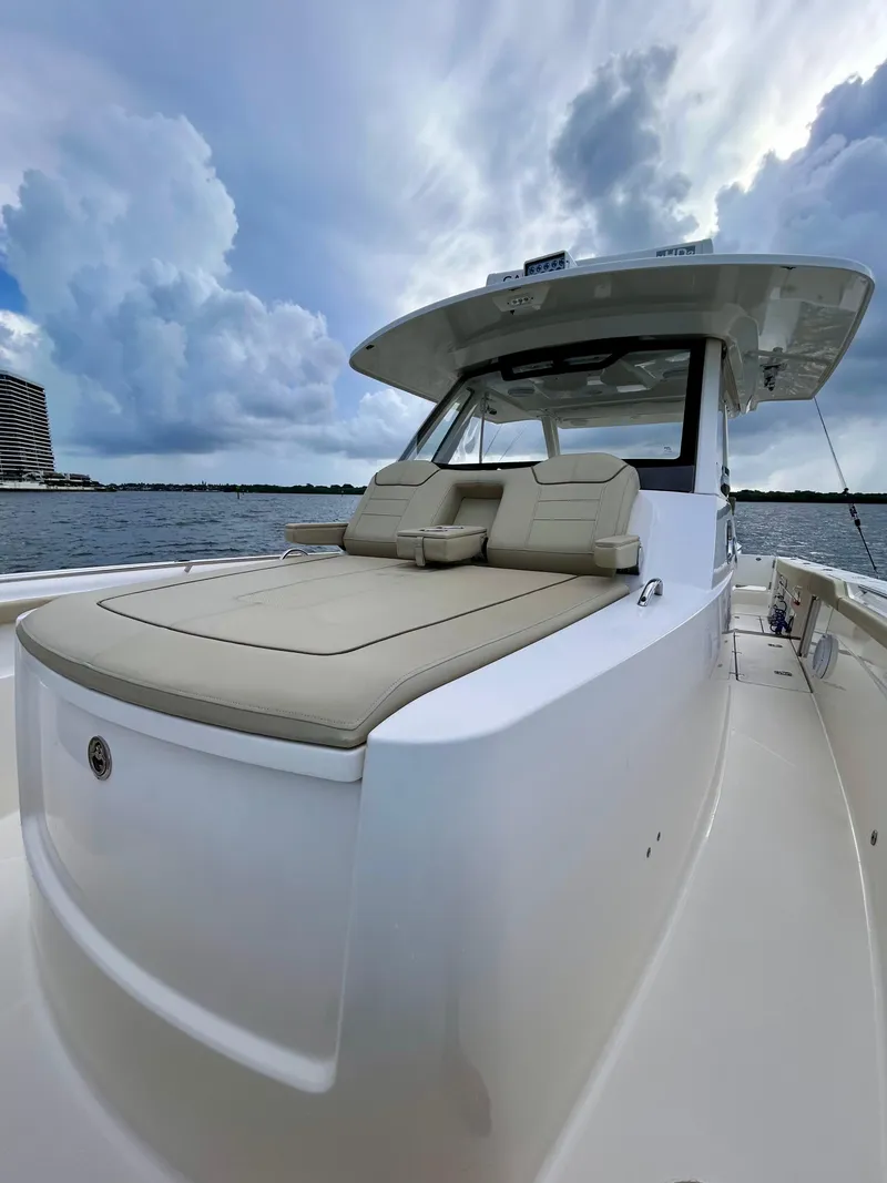 Slide: The Image of 2018 Pursuit S 368 Sport boat with cushioned seating, under a cloudy sky on the water. - 8